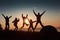 A silhouette of group people have fun at the top of the mountain near the tent during the sunset