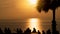Silhouette of group of young people, friends, team standing enjoying together see orange sky at sunset over sea ocean