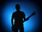 Silhouette guitarists of a rock band with guitar on blue background