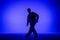 Silhouette of guy in casual clothes dancing elements of hip hop in studio with blue light. Dancer demonstrates body