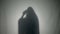 Silhouette of a Halloween possessed woman ghost dialing a phone number and threatening the living ones behind the glass -