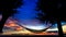 Silhouette of Hammock suspended between two trees on the beach with beautiful sunset sky