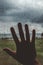 Silhouette of a hand touching a window full of water drops