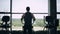 Silhouette of handsome man at the gym exercising on the strainer machine. Dolly shot left to right