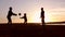 Silhouette, happy child with mother and father, family at sunset, summertime. Run, raising baby up in the air, hugs, love, playing