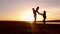 Silhouette, happy child with mother and father, family at sunset, summertime. Run, raising baby up in the air, hugs, love, playing