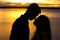 Silhouette of happy couple in love kissing romantic at sunset.