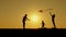 Silhouette of a happy family against the sunset sun. A man and two children playing with a kite in nature. Education and