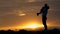 Silhouette of happy family father of mother and two sons playing outdoors in field at sunset