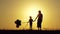 Silhouette of a happy family at sunset. A mother and a child with balloons hold each other`s hands.