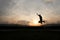 Silhouette of happy man jumping at sunset