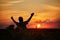 Silhouette of happy successful corn farmer in cornfield in sunset with arms raised in the air