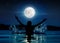 Silhouette of happy woman raising arms in a swimming pool under the full moon