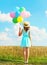 Silhouette happy woman stands with an air colorful balloons in a straw hat enjoying a summer day on field and blue sky backgroun