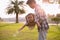 A silhouette of a happy young father harmonious family outdoors laughing and playing in the summer on the sunset background.