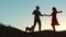 Silhouette of a happy young married couple and dog slow dancing outside at sunset. slow motion video. man and girl