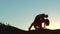Silhouette of a happy young married couple and dog slow dancing outside at sunset. slow motion video. man and girl
