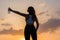 Silhouette of happy young woman in the sport clothes with bottle of clear mineral water on the sunset sky backgrounds. The concept