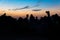 Silhouette head shot of camel and camel herders at sunset.