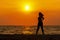 Silhouette healthy woman lifestyle exercising vital meditate and practicing yoga on the rock in beach at sunset.