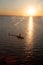 The silhouette of a helicopter against the dark sunset sea.