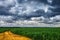 Silhouette of the high voltage electric pylon towers on the background of beautiful storm clouds near yellow sand road