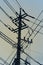 Silhouette of highly loaded urban electricity pole with many cables against orange sunset sky