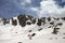 Silhouette of hiker in red and dog on snowy plateau in high mountain at sunny day