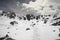 Silhouette of hiker in red on snowy plateau in high mountains at sunny day