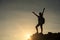 Silhouette hiker woman raise hands to celebrate after climbing to mountain summit at sunset. Extreme outdoor adventure sport