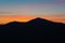 Silhouette of hill`s ridge with naked trees and beautifully colored twilight sky