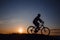 Silhouette of a hipster man on a bicycle on sunset background