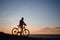 Silhouette of a hipster man on a bicycle on sunset background