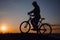 Silhouette of a hipster man on a bicycle on sunset background