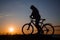 Silhouette of a hipster man on a bicycle on sunset background