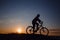 Silhouette of a hipster man on a bicycle on sunset background