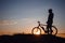 Silhouette of a hipster man on a bicycle on sunset background