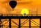 Silhouette hot air balloons floating over old wooden bridge in sangklaburi, thailand on sunset