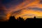 Silhouette of house and tree at evening dawn with orange sky