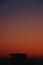 Silhouette houses in a distance under orange evening sky, vertical shot