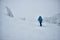 Silhouette of human in blue winterwear moving among snow