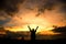 Silhouette of human Raise two arms. Golden color of dramatic clouds and sky after sunset.