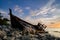 Silhouette image of abandon shipwrecked on rocky shoreline. dark cloud and soft on water