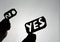 Silhouette image of a hands holding papers with the words YES and NO