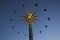 Silhouette image of people swinging high in the sky on an amusement park ride in the evening