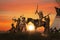 Silhouette of indian and cowboy together in group with rifle and gun and arrow during sunset