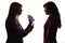 Silhouette of an indignant mother with a daughter`s phone, a teenager is afraid