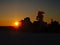 Silhouette of industrial buiding with smoke plumes against the sunset sky