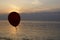 Silhouette of an inflatable ball on a string against the background of the sunset over the sea