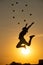 Silhouette of juggler jumping with balls on colorful sunset